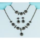 A silver and garnet three piece set comprising necklace, bracelet and earrings