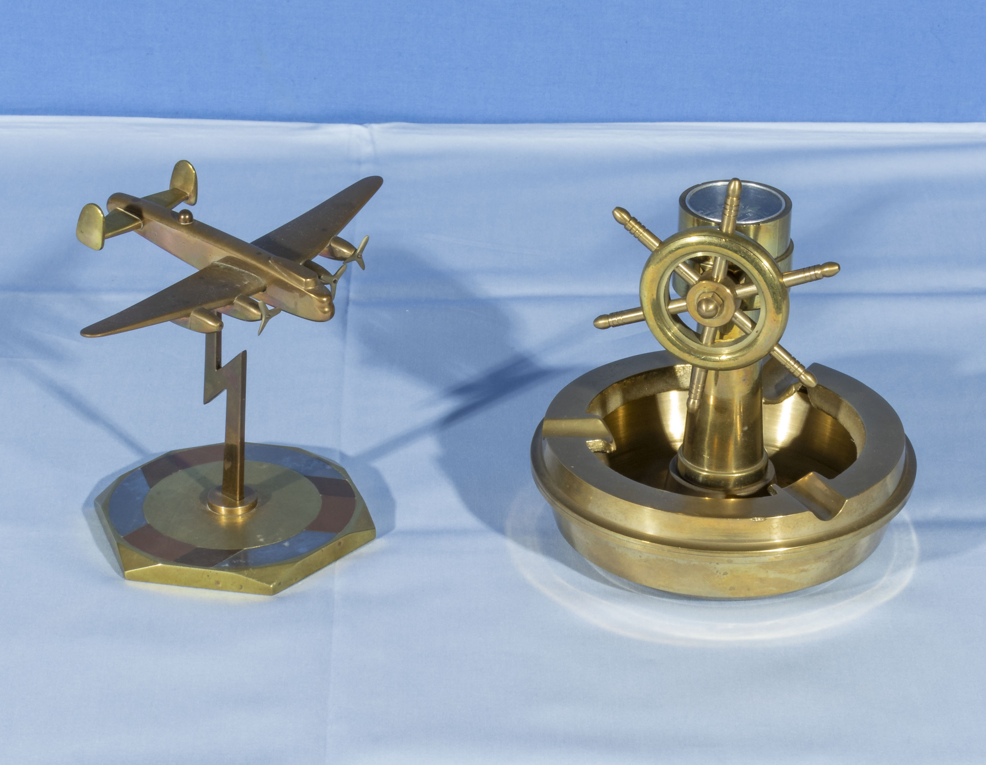 A brass bomber aeroplane desk decoration together with a brass nautical ash tray