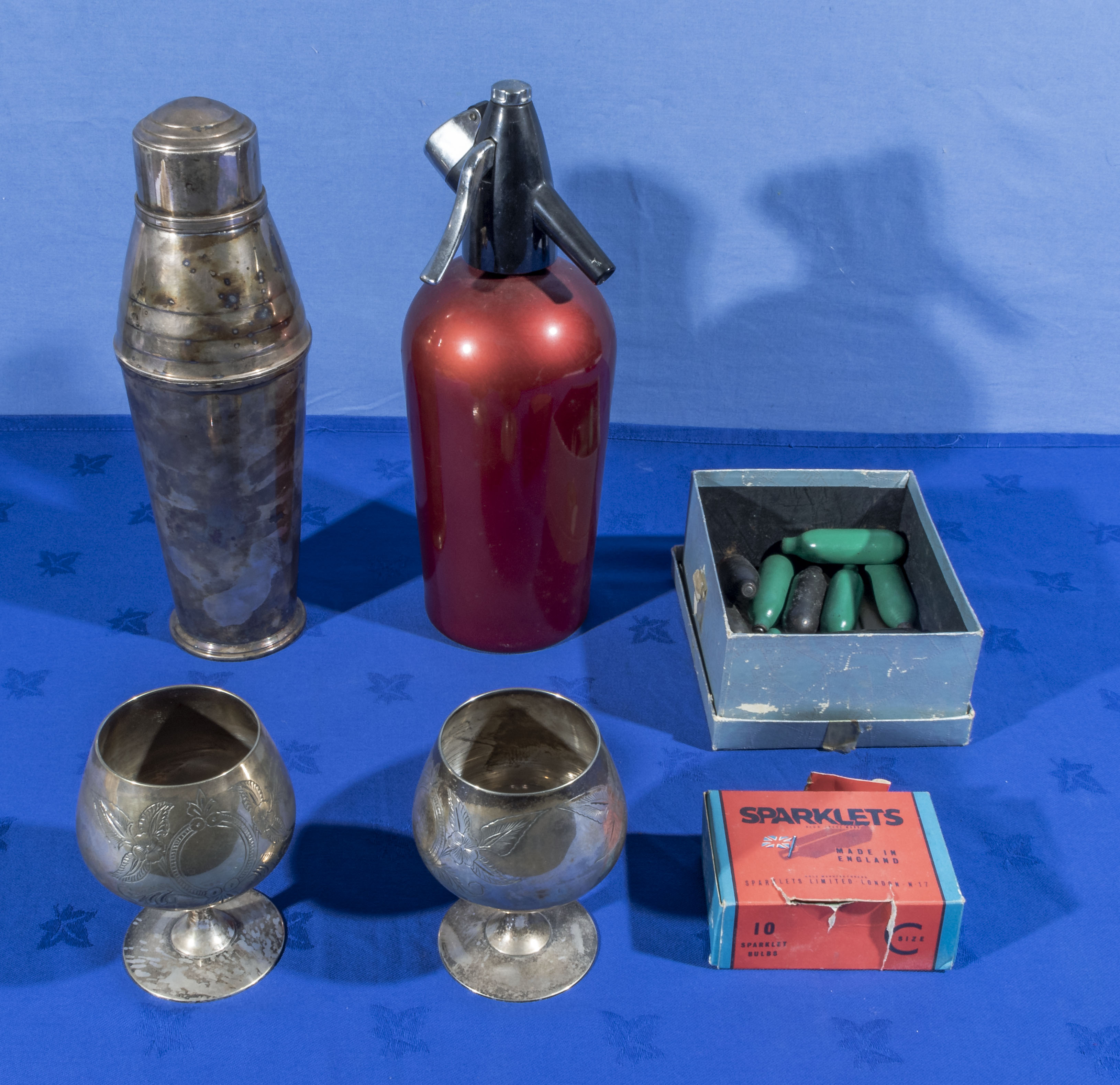 A vintage sparklets soda syphon and bulbs, cocktail shaker and two goblets