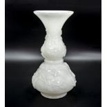 An opaque white glass vase with raised floral decoration
