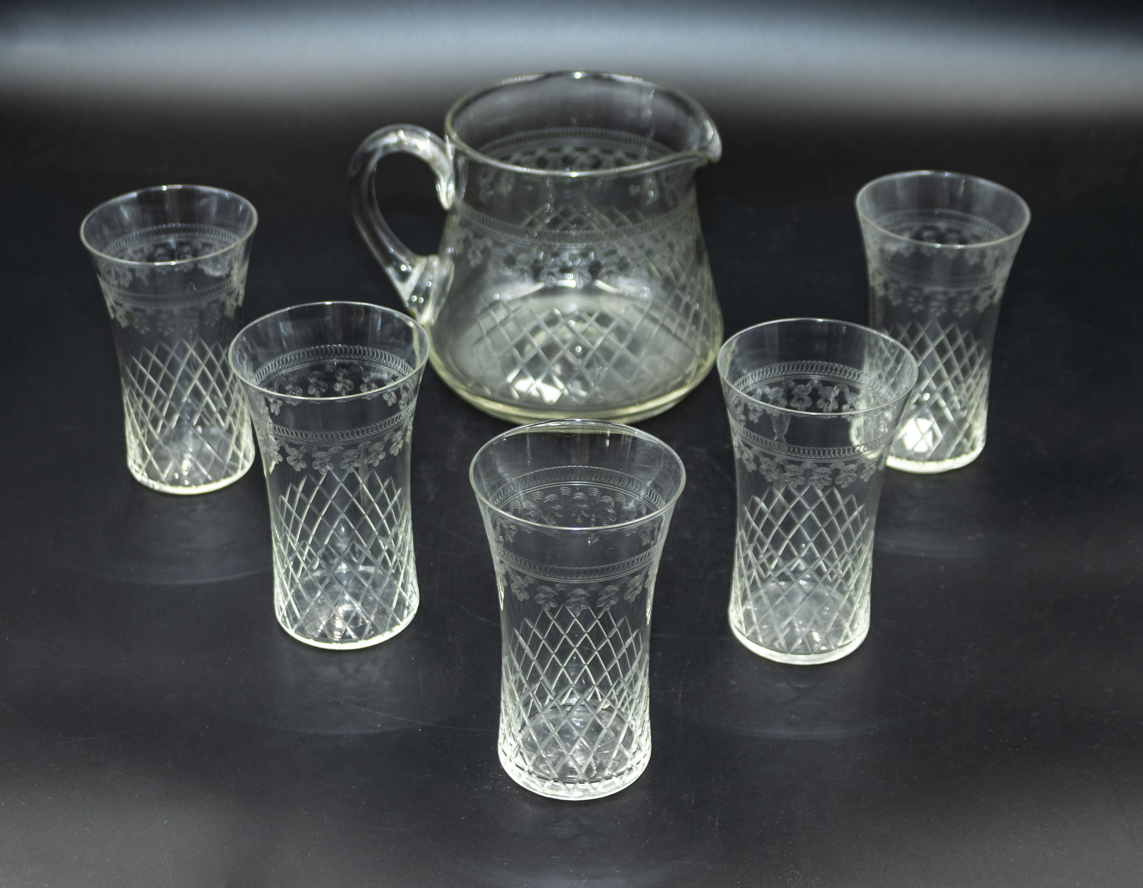 An etched glass pitcher and five glasses