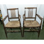 A pair of antique oak arm chairs with rush seats.