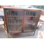 A 1930's oak bookcase with a pair of lead glazed doors on barley twist legs, 138 h x 137cm w