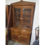 A late 19th/early 20th century bookcase having a floral carved pediment above two glazed doors and