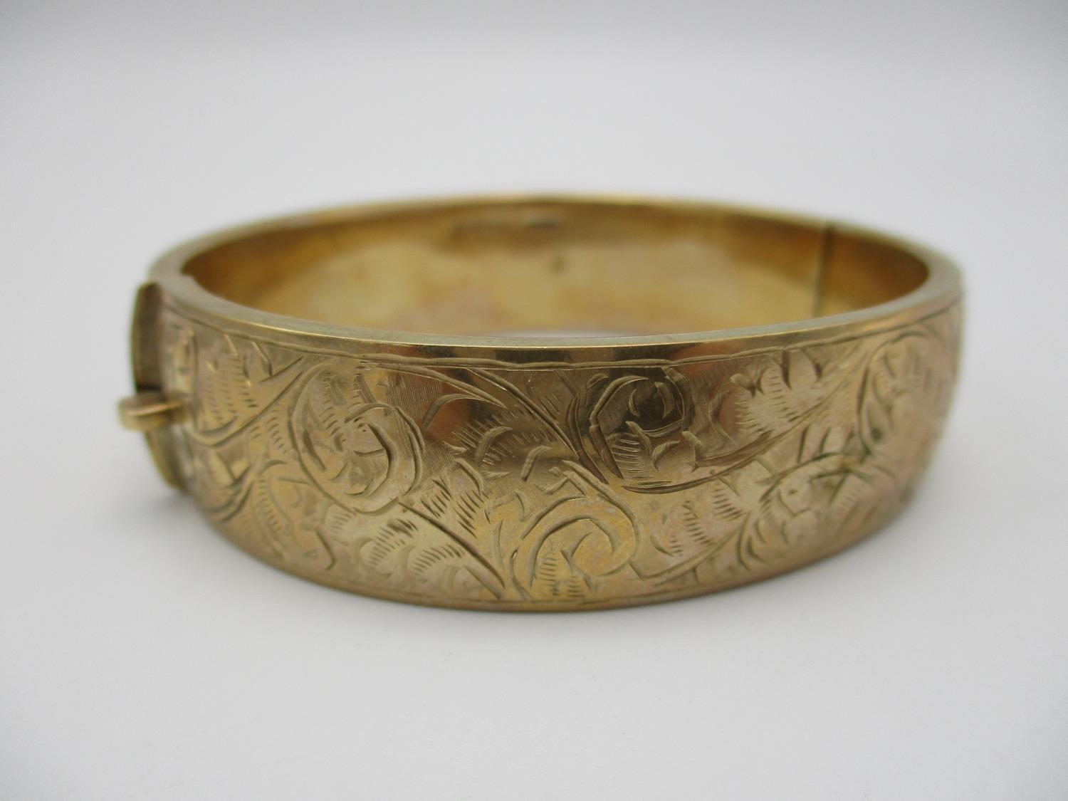 A 9ct gold engraved bangle, designed with etched scrolls of foliage throughout the exterior, 5.8