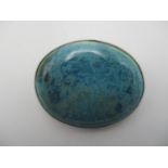A silver and Ruskin ceramic brooch, with central speckled blue cabochon in a sterling silver