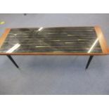A mid 20th century coffee table with a black and white glass top on turned black legs