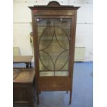 An Edwardian display cabinet having a bow, shell and floral decoration, two internal glass shelves