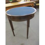 A 1920's mahogany games table in circular form having a navy felt covered top above tapering dart