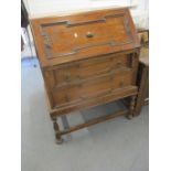 A 1930's oak bureau with two drawers, on turned black legs