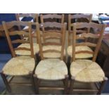 A set of six beech kitchen chairs having ladder backs and rush seats