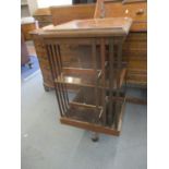 An early 20th century mahogany revolving bookcase with a crossbanded border over slatted sides, on