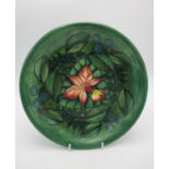 A Moorcroft shallow plate designed by Sally Tuffin, in the Rainforest pattern on green ground with
