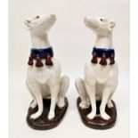 A pair of Continental majolica models of seated hound dogs, possibly Italian, wearing blue studded