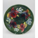 A Walter Moorcroft shallow plate in the orchid pattern on green ground, with signature, impressed