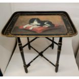 A Victorian painted tole tray with stand depicting a King Charles spaniel on a red cushion, with