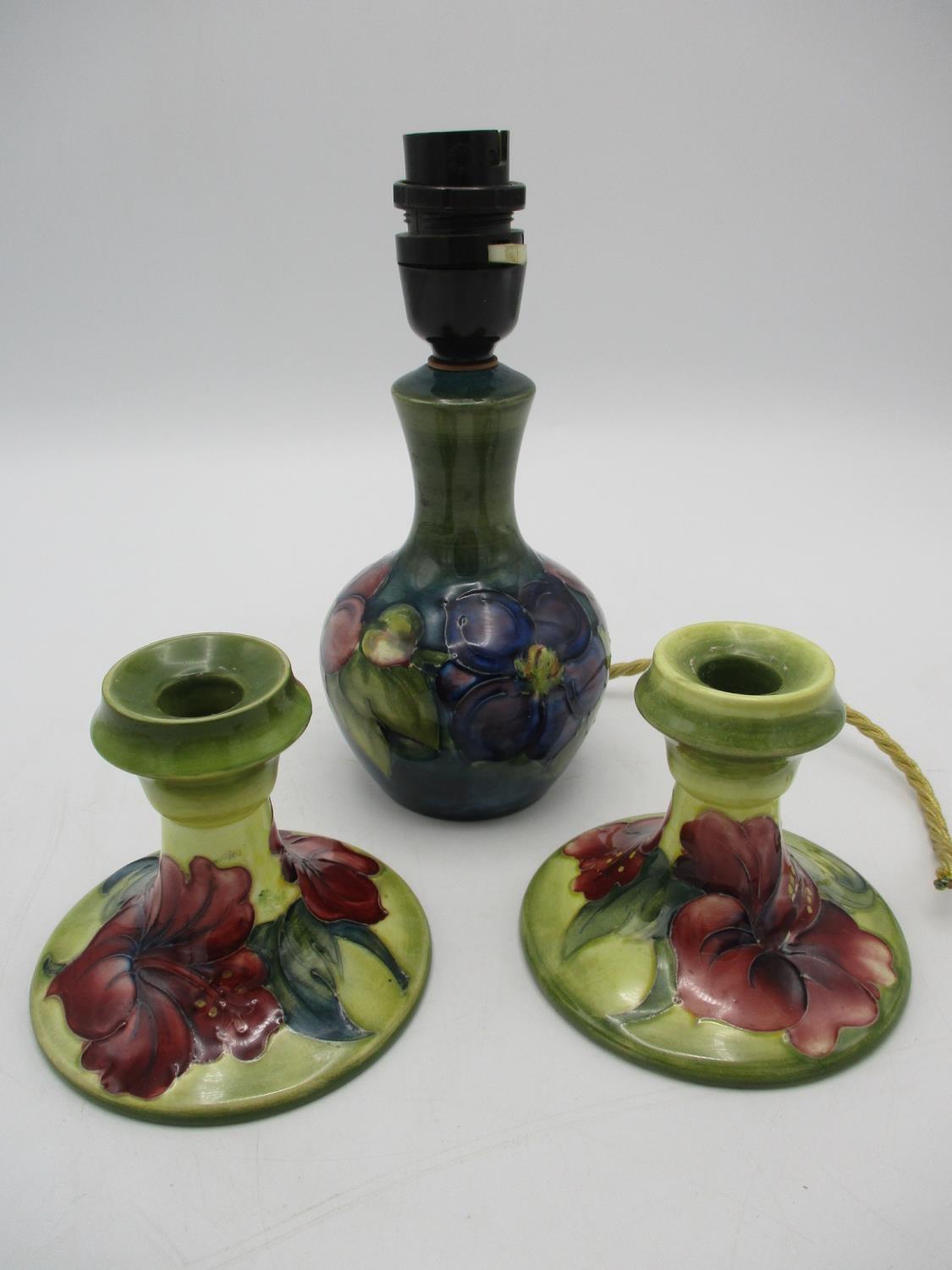 A pair of Moorcroft dwarf candlesticks, in the Hibiscus pattern on green ground, impressed backstamp