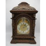 Circa 1900 an oak carved mantel clock, the arched top dial having a silvered chapter ring with Roman