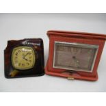 Two early 20th century 8 day travel clocks to include a C Bucherer clock in a pink leather folding