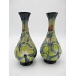A pair of modern Moorcroft bottle vases, with tube lined floral design throughout, initialled GP