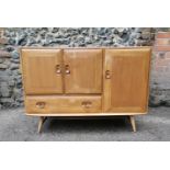 An Ercol blonde elm sideboard, model 467, with double doors above a twin handle drawer and flanked