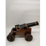 An early 20th century British model of a cast iron pounder cannon, painted black and gold, mounted