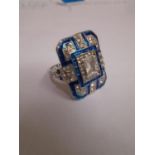 In the Art Deco style, a plaque ring set white paste stones and blue enamel, UK ring size P/Q