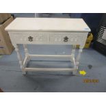 A distressed cream painted side table with twin drawers, on turned block legs