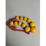 An East Asian graduated faux amber bead necklace with white metal separators, tied with pleated