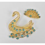 A gold and turqoise brooch in the shape of a swan swimming, designed with filigree scrolls and