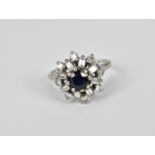 A white gold, sapphire and diamond snowflake cluster ring, with central sapphire flanked with