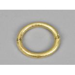 An 18ct yellow gold bangle, of hollow round section with textured design and box clasp, inner
