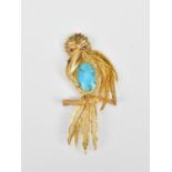 A gold, ruby and turquoise brooch in the shape of a bird, with filigree detail to the head, body,