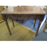 Circa 1880, a Victorian baronial carved side table with apron drawer, scrolled swags, turned candy