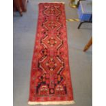 A small handwoven Middle Eastern runner, red ground with a line of four elephant gulls, geometric