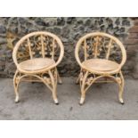 A pair of rattan conservatory chairs, designed with stylised floral scrolls, circular wicker seat,
