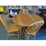 A pine extending kitchen table with rise and fall leaf, and four winder wheel back style kitchen