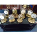 A group of anniversary and electric clocks, most under glass or plastic domes, to include Junghans