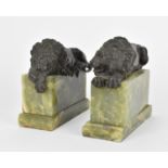 A pair of early 20th century patinated bronze models of recumbent lions after Antonio Canova, raised