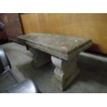 A weathered garden concrete bench resting on two ornate pillar ends Location: G