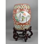 A 20th century Chinese Famille Verte porcelain garden seat decorated with shaped panels of figures