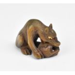 A Japanese cared wood netsuke, 19th century, modelled as a wolf and skull, with textured hair,