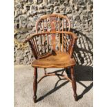 A Georgian ash and elm comb back Windsor armchair with pierced central splat turned legs and