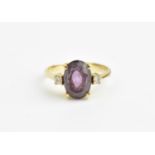 An 18ct yellow gold, amethyst and diamond dress ring, with central oval cut amethyst flanked