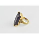 A large yellow metal and amethyst dress ring, with central oval amethyst flanked with paste stones,