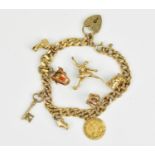 A 9ct yellow gold flat curb link charm bracelet, with multiple charms such as a crown, a toby jug, a
