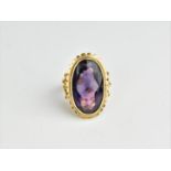 A large 18ct yellow gold and amethyst dress ring, with central oval shaped amethyst, within a petal