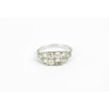 An Art Deco style white metal and diamond dress ring, set with a central set of three diamonds (