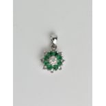 An 18ct white gold, diamond and emerald floral cluster pendant, with central illusion set diamond,