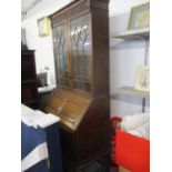 A 1930's oak bureau bookcase with blind fretwork cornice, glazed doors A/F, the central fall flap